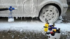 Car wheels being cleaned with foam spray and bottles nearby