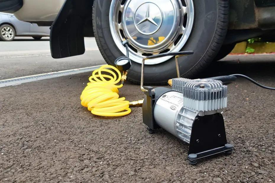 Portable air compressor inflating car tire on roadside